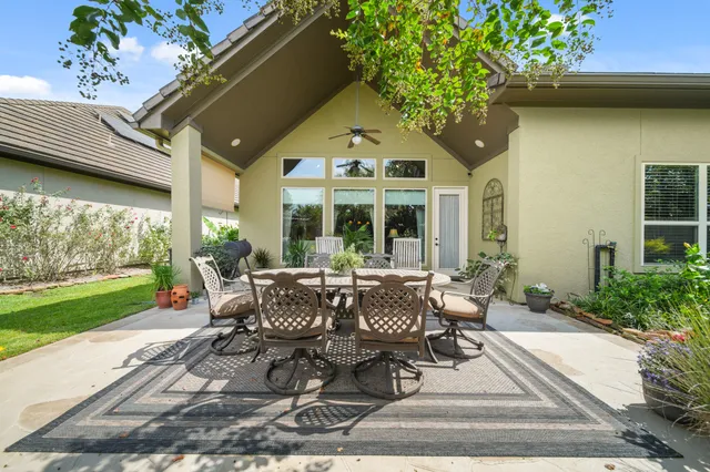 a view of a patio with table and chairs potted plants and floor to ceiling window
