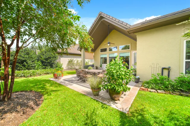 a view of a house with a big yard plants and large trees