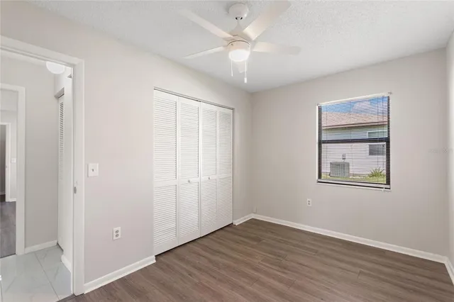 a view of an empty room with wooden floor and a ceiling fan