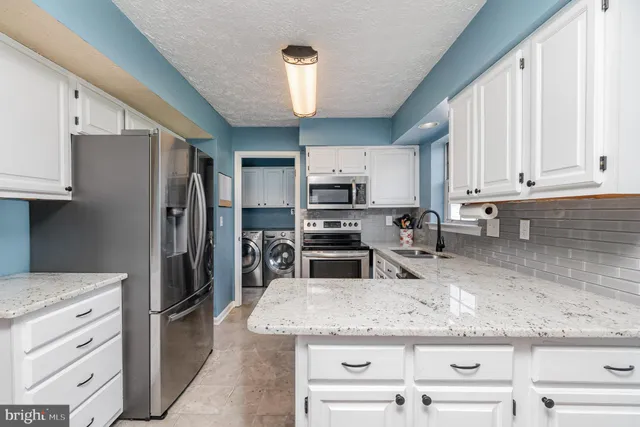 a kitchen with granite countertop a refrigerator stove and kitchen island