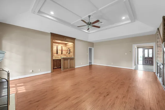 a view of an empty room with wooden floor and a ceiling fan