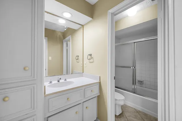 a bathroom with a granite countertop toilet a sink and a mirror