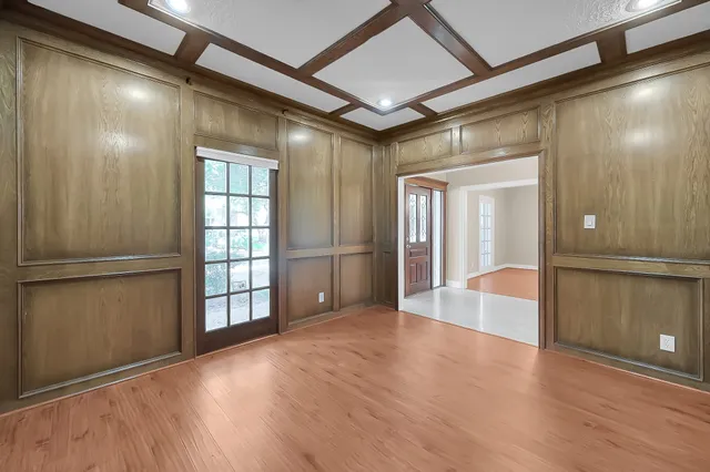 an empty room with wooden floor chandelier and windows