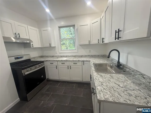 a kitchen with granite countertop a sink stove and cabinets