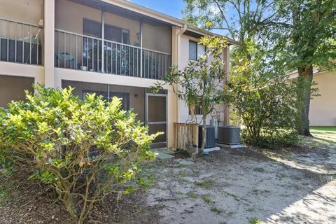 a view of a house with a small yard and large tree