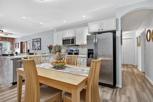 a kitchen with stainless steel appliances granite countertop a stove a sink dishwasher and a refrigerator with white cabinets