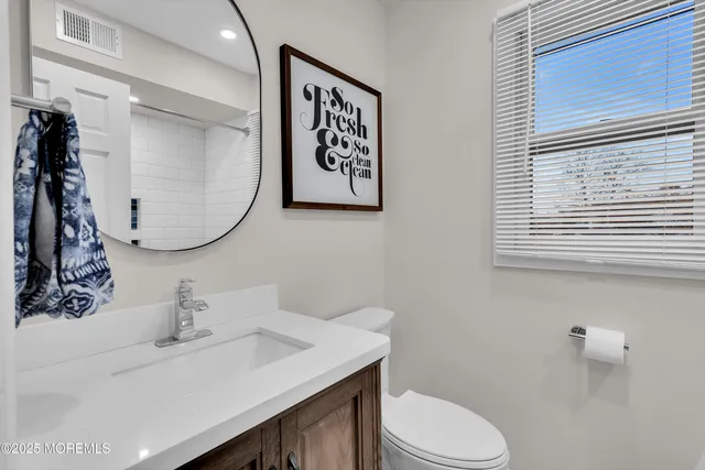 a bathroom with a sink vanity mirror and toilet