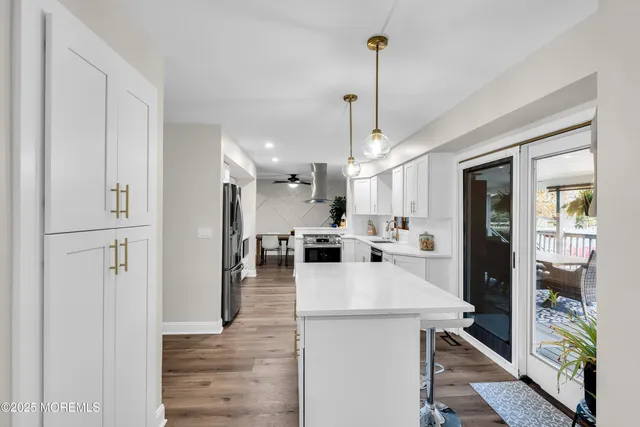 a view of a kitchen with kitchen island a counter space appliances and a ceiling fan