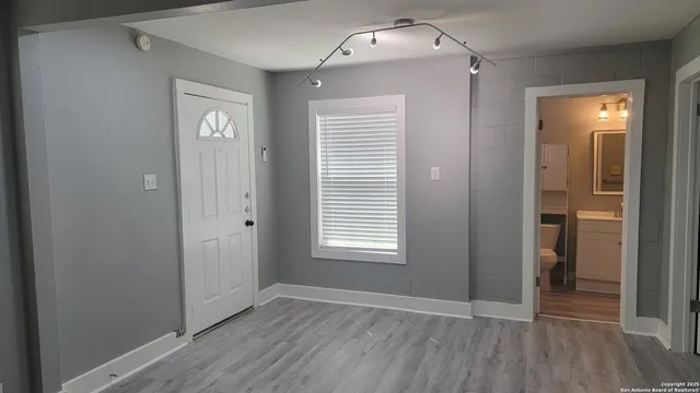an empty room with wooden floor closet and windows