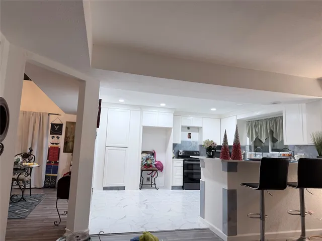 a view of kitchen with stainless steel appliances kitchen island refrigerator stove dining table and chairs