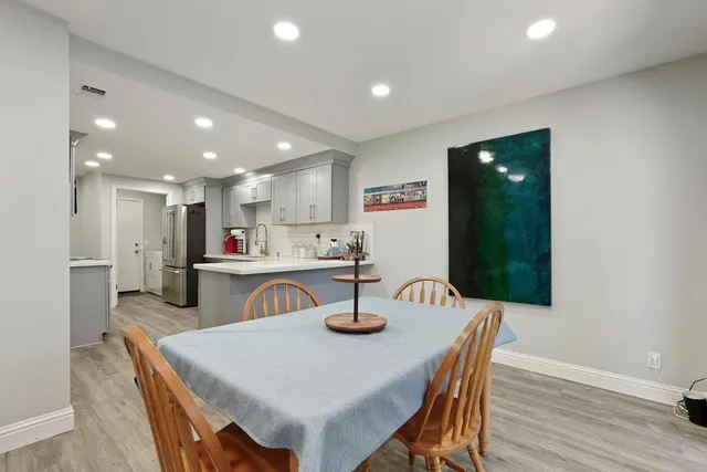 a kitchen with stainless steel appliances granite countertop a sink a stove a dining table and chairs