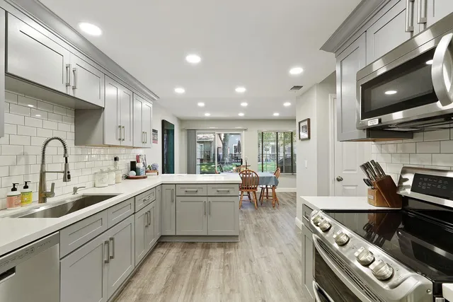 a open kitchen with stainless steel appliances granite countertop a sink a stove and cabinets