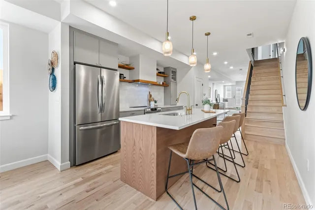 a kitchen with stainless steel appliances granite countertop a refrigerator a sink dishwasher a dining table and chairs with wooden floor