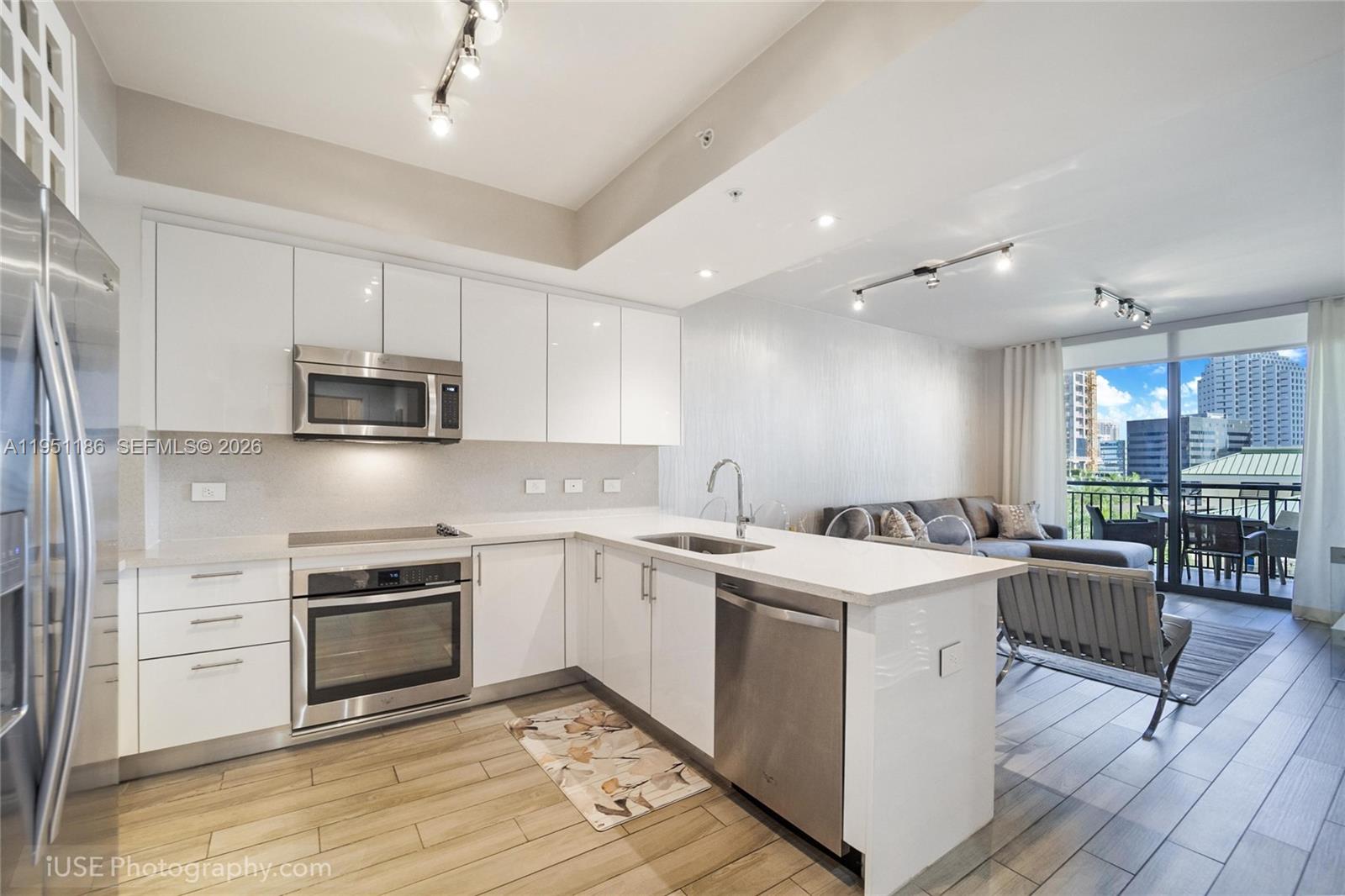 999 Southwest 1st Avenue, Unit 1208 Miami, FL 33130 - Photo 3 of 17 a open kitchen with stainless steel appliances granite countertop a stove top oven a sink dishwasher a dining table and chairs with wooden floor