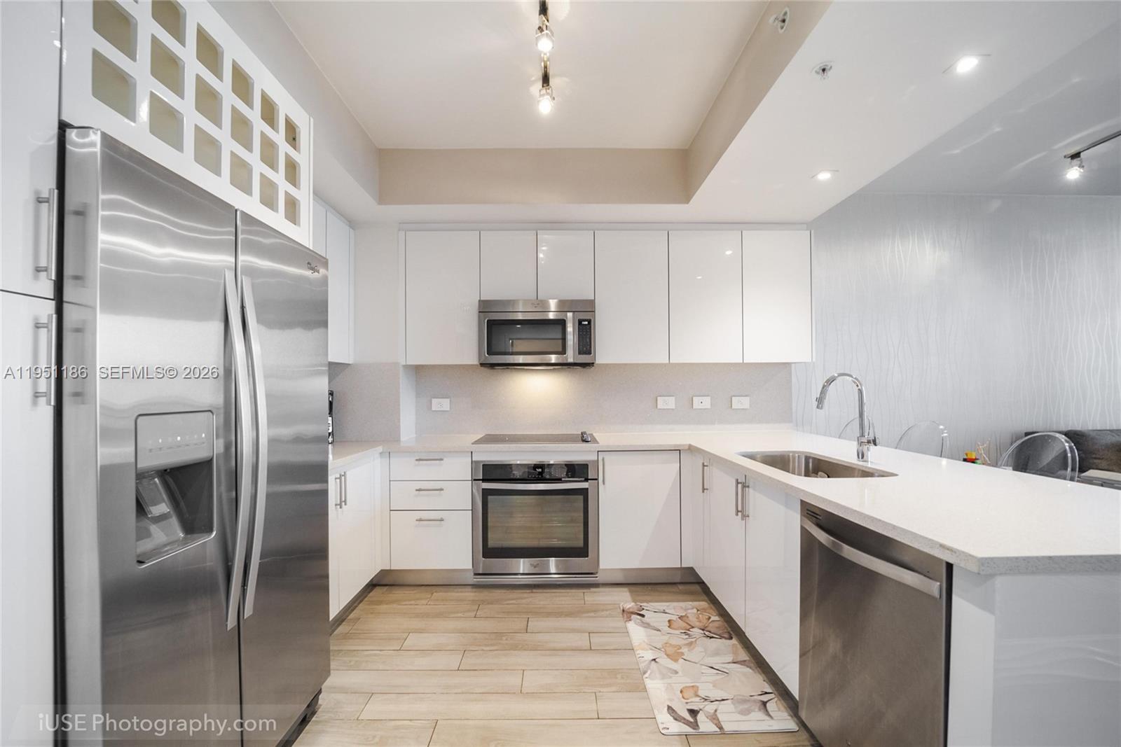 999 Southwest 1st Avenue, Unit 1208 Miami, FL 33130 - Photo 4 of 17 a kitchen with a sink stainless steel appliances and cabinets