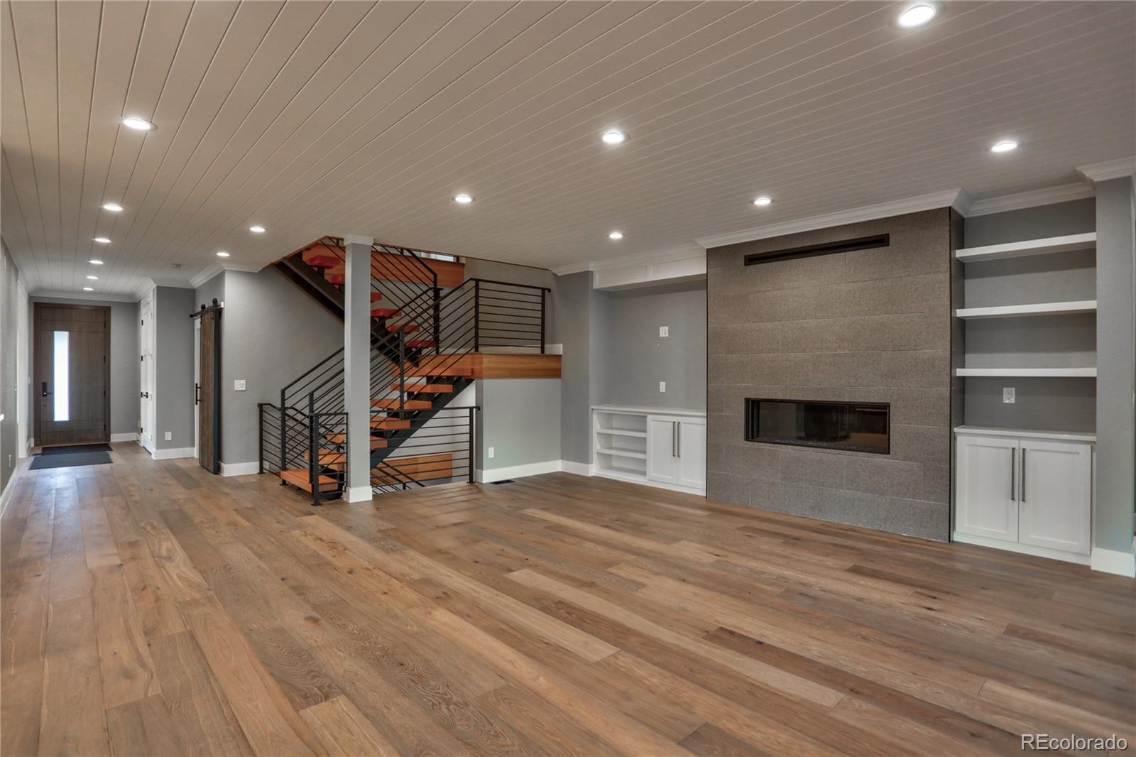 2732 South Jackson Street Denver, CO 80210 - Photo 12 of 40 a view of an empty room with wooden floor stairs and a fireplace