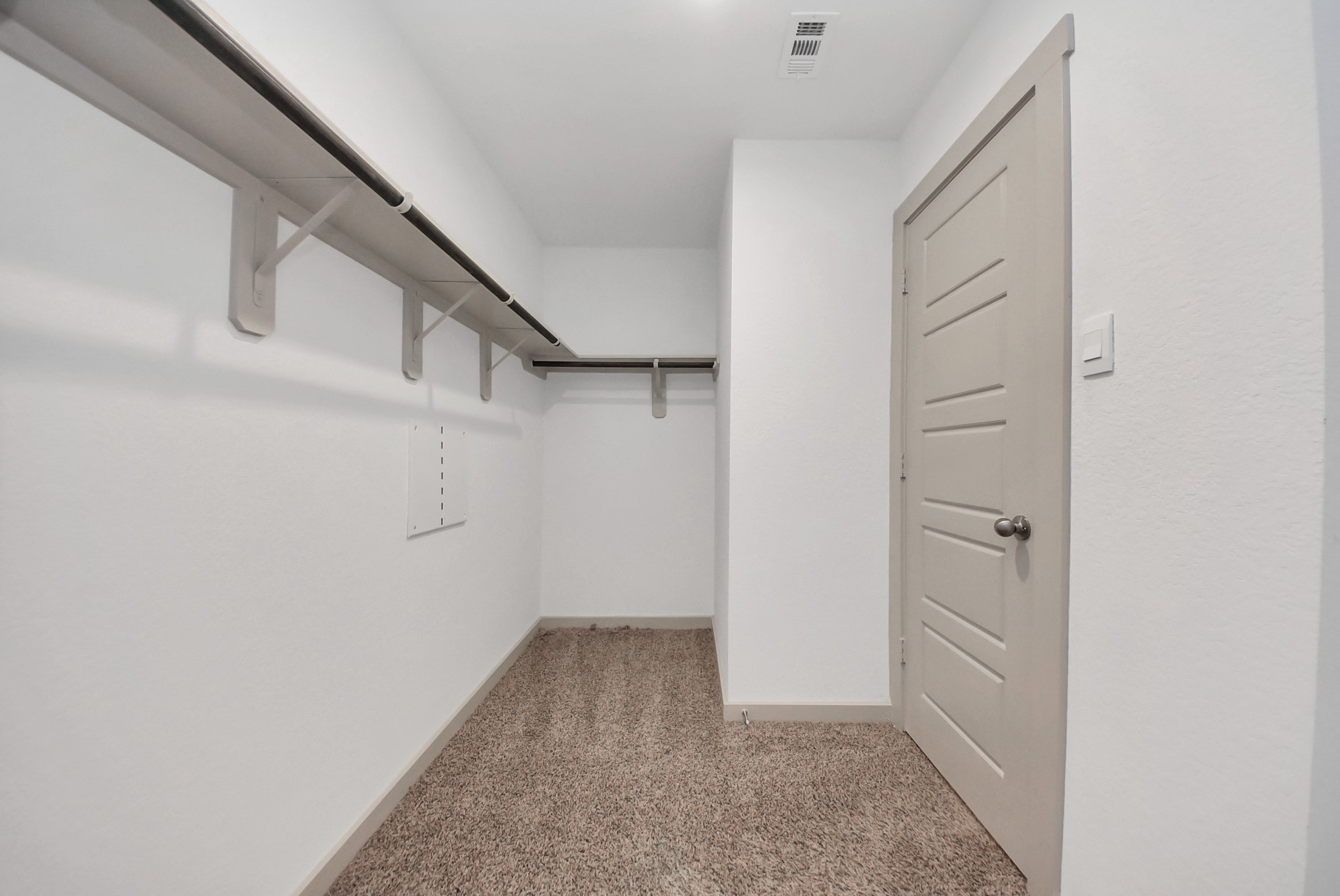 7911 Wrangler Shack Lane Rosharon, TX 77583 - Photo 34 of 40 Spacious walk-in closet featuring ample shelving and hanging space, complemented by soft carpet flooring and a sleek, modern door design.