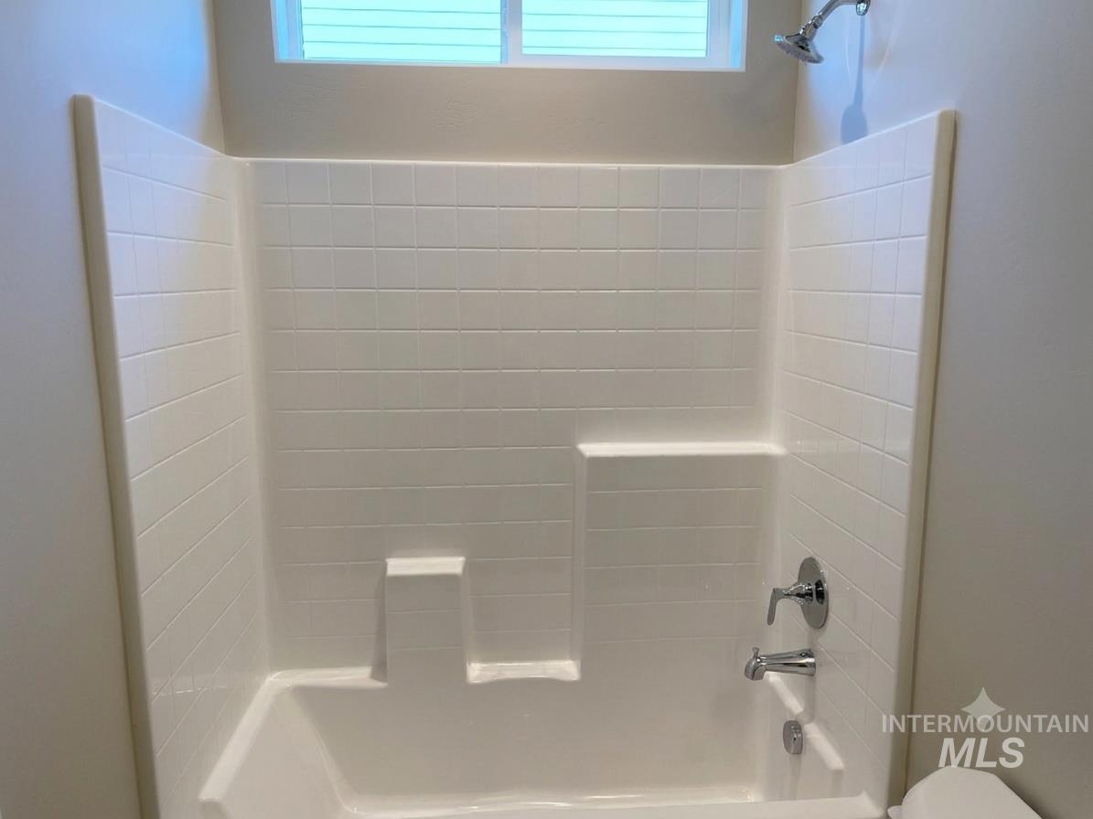 994 Kenbrook Loop Twin Falls, ID 83301 - Photo 10 of 10 Bathtub and shower combination featuring a white tiled surround, integrated shelving, and a chrome showerhead with matching faucet