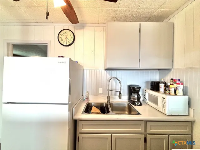 a white refrigerator freezer and a stove sitting inside of a kitchen