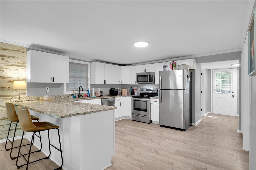 115 May Street Easley, SC 29640 - Photo 7 of 25 Gleaming stone countertops and stainless steel appliances elevate this bright, open kitchen space.