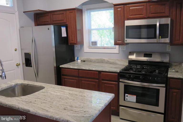 3819 Barrington Road Baltimore, MD 21215 - Photo 12 of 19 a kitchen with granite countertop wooden cabinets and stainless steel appliances