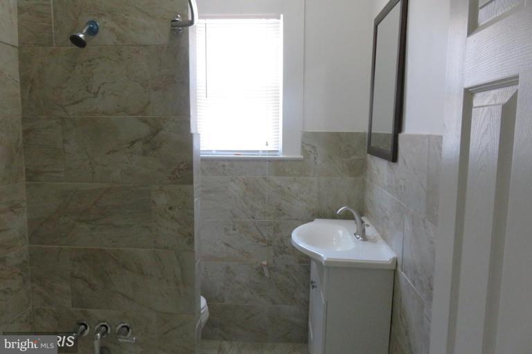 3819 Barrington Road Baltimore, MD 21215 - Photo 15 of 19 a bathroom with a sink a window and shower