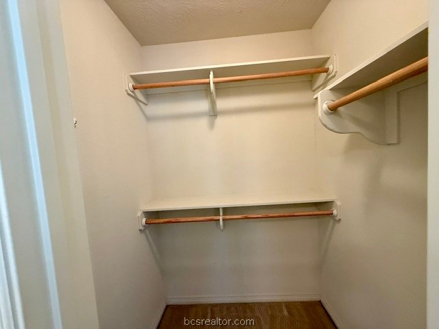 1000 Spring Loop, Unit 1806 College Station, TX 77840 - Photo 13 of 33 Walk-in closet featuring light-colored walls, wood-finish flooring, two upper shelves, and two lower hanging rods