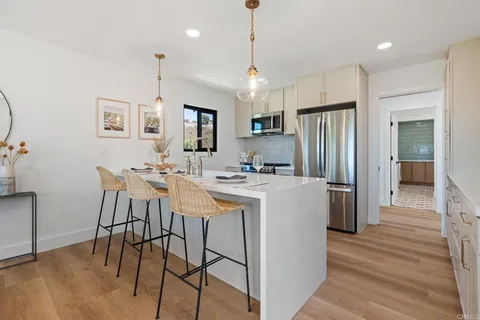 a kitchen with stainless steel appliances a dining table chairs refrigerator and sink