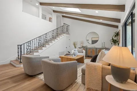 a living room with couches a fireplace and a dining table with wooden floor