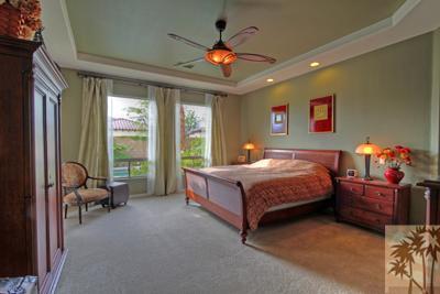 81129 Soaring Hawk Court Indio, CA 92201 - Photo 17 of 25 a spacious bedroom with a bed and a chandelier