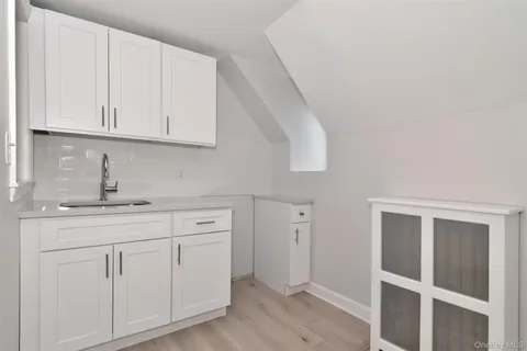 a kitchen with white cabinets and sink
