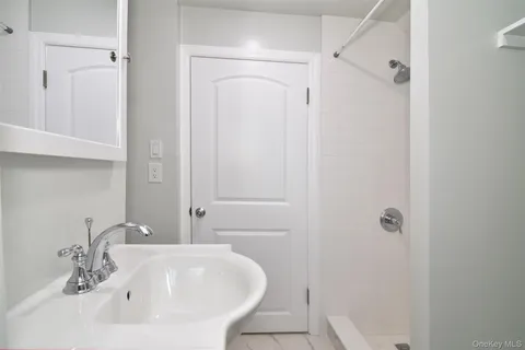 a bathroom with a white sink a shower and a mirror