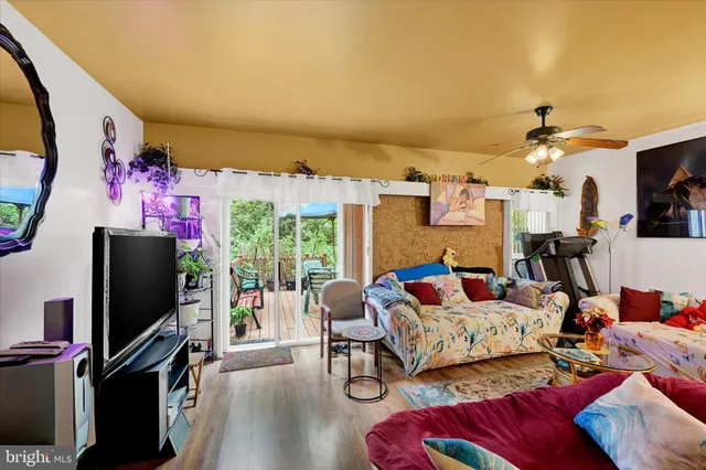a living room with furniture a flat screen tv and a floor to ceiling window
