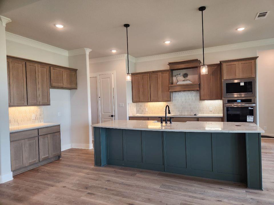 2305 Gypsum Street Krum, TX 76249 - Photo 9 of 22 Spacious kitchen featuring a large central island, wood-finish flooring, recessed lighting, and pendant fixtures