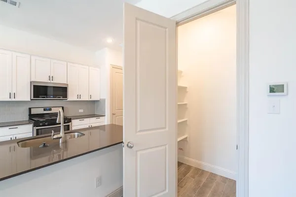 a kitchen with stainless steel appliances a refrigerator and white cabinets