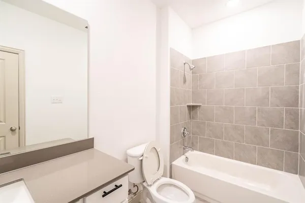 a bathroom with a granite countertop bathtub shower sink vanity and toilet