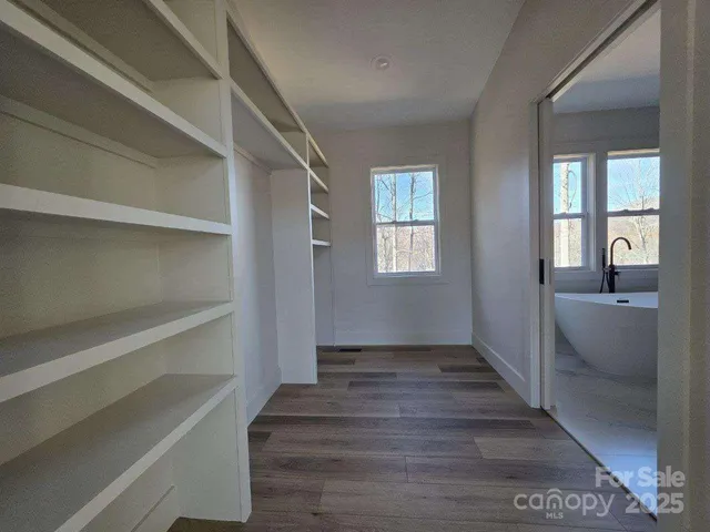 a view of a hallway view with wooden floor and a bathroom