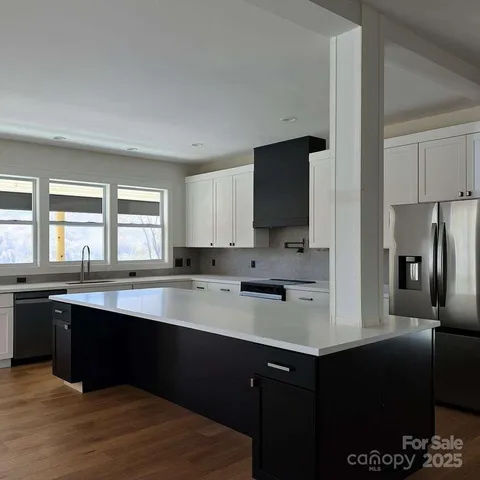 a kitchen with stainless steel appliances granite countertop a sink a stove a refrigerator and cabinets
