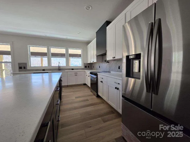 a large kitchen with stainless steel appliances a refrigerator sink and cabinets
