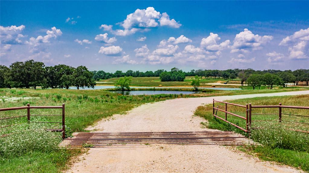 1789 Brumelow Road Whitesboro, TX 76273 - Photo 2 of 30 Gravel road with cattle guard leading to open fields, multiple ponds, and mature trees