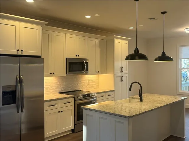 a kitchen with stainless steel appliances granite countertop a sink a stove and a refrigerator