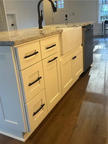 a close view of a sink and dishwasher with white cabinets