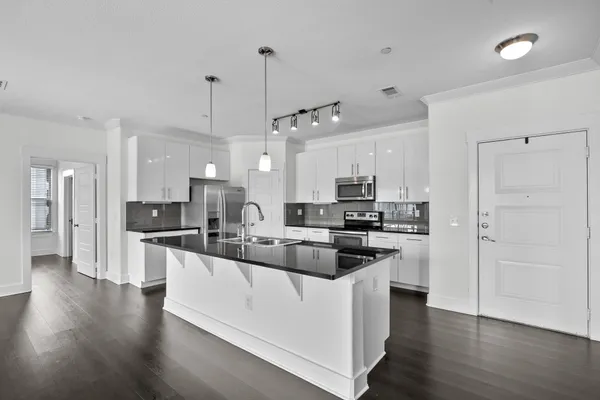 a kitchen with stainless steel appliances granite countertop a sink a stove a refrigerator and island with wooden floor