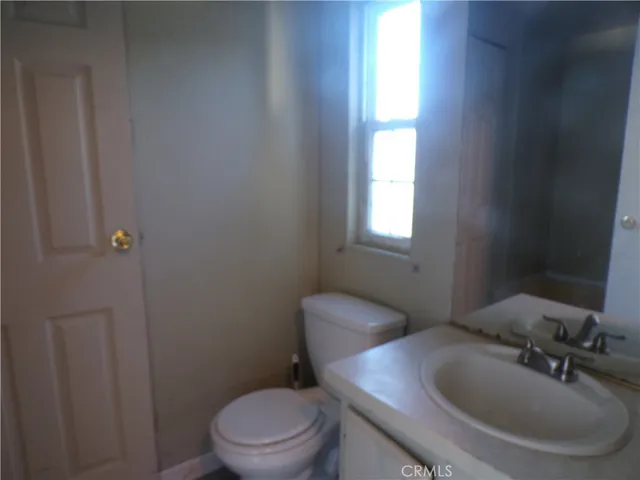 a bathroom with a toilet a sink a mirror and a window