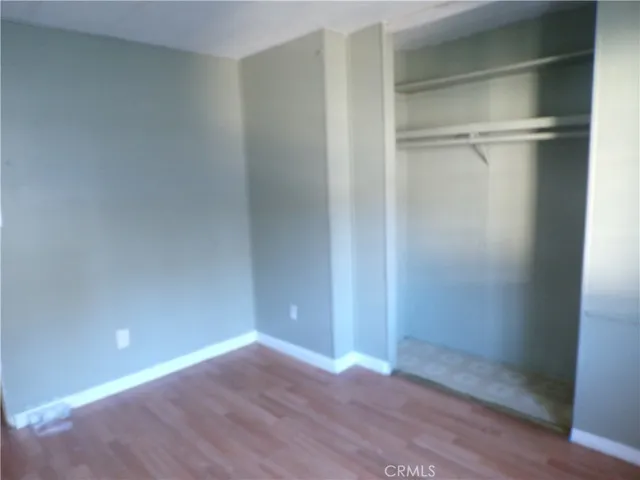 a view of an empty room with wooden floor and closet