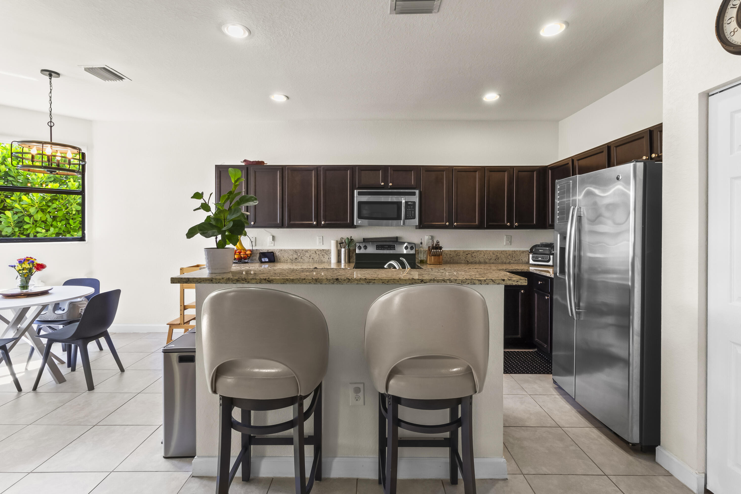 11823 Southwest 151st Place Miami, FL 33196 - Photo 15 of 53 a kitchen with stainless steel appliances granite countertop a refrigerator and a dining table