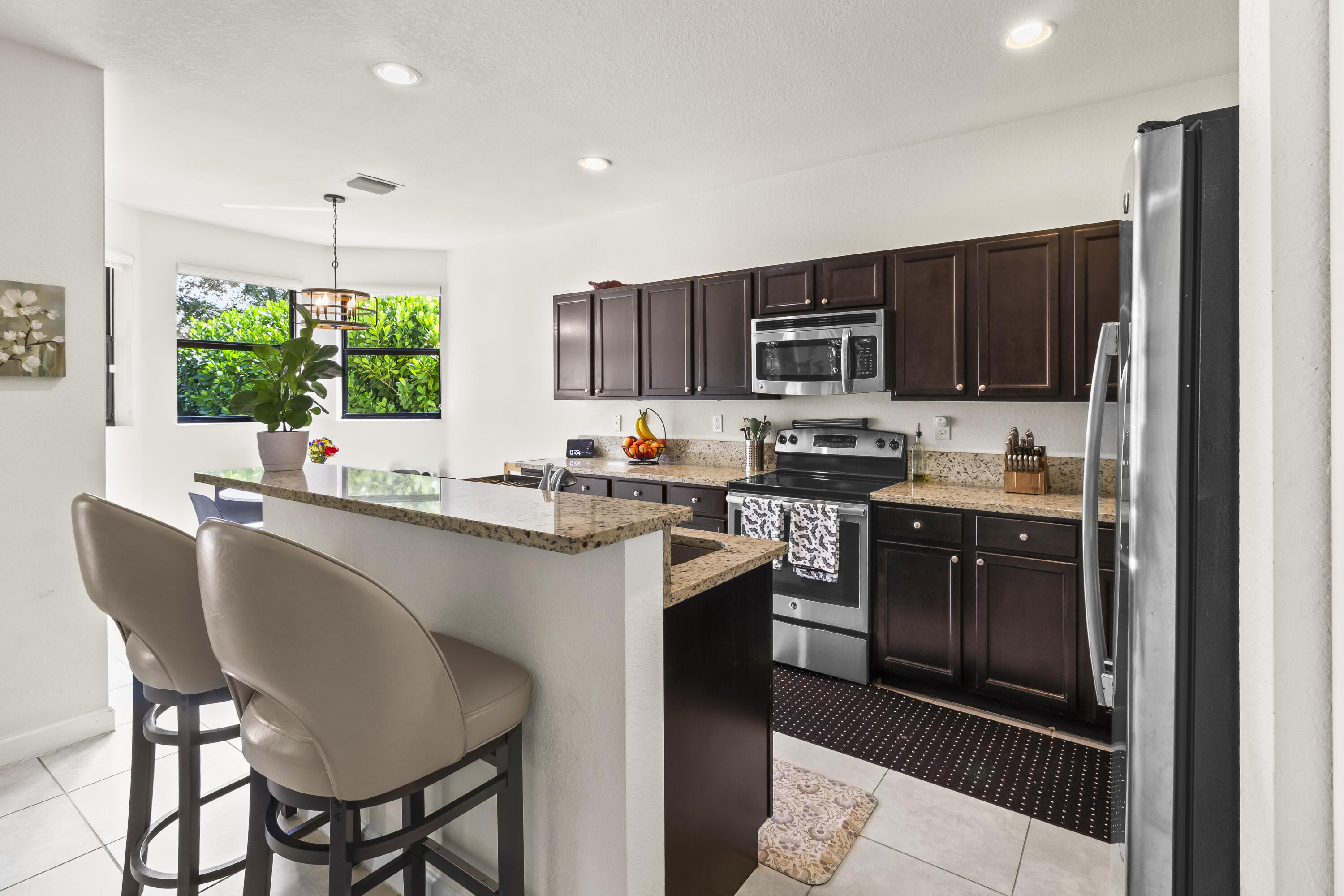 11823 Southwest 151st Place Miami, FL 33196 - Photo 16 of 53 a kitchen with stainless steel appliances granite countertop a stove a sink dishwasher a microwave oven and a refrigerator with wooden floor