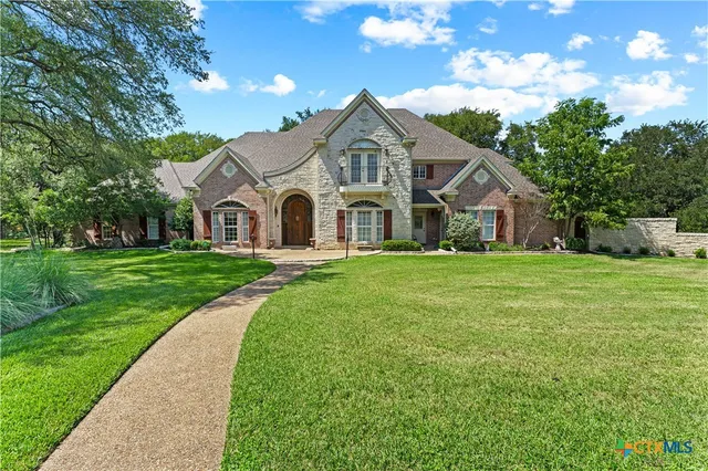 a view of a white house that has a big yard with large trees