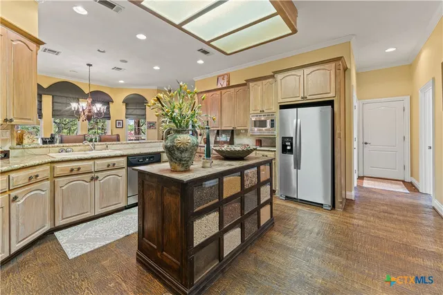 a kitchen with stainless steel appliances granite countertop a refrigerator a sink a stove and a wooden floors