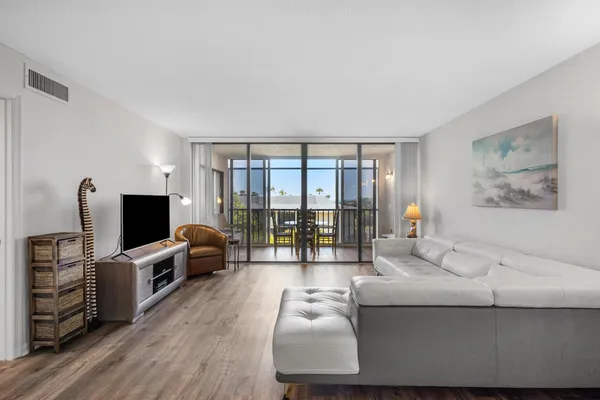 a living room with furniture a flat screen tv and a floor to ceiling window
